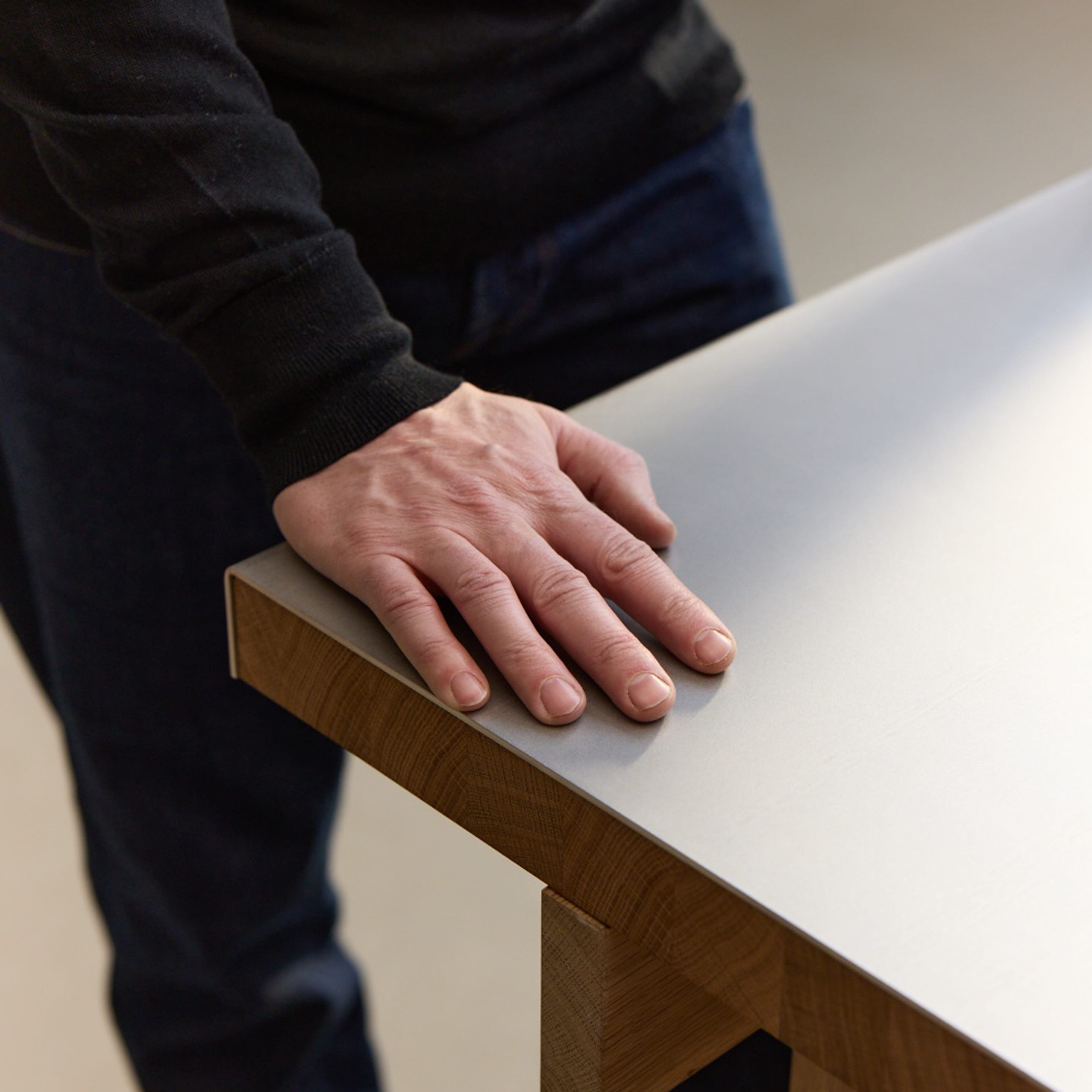 Eine Hand liegt auf der Oberfläche von The Bench – Massivholz Eiche mit Edelstahl-Oberfläche